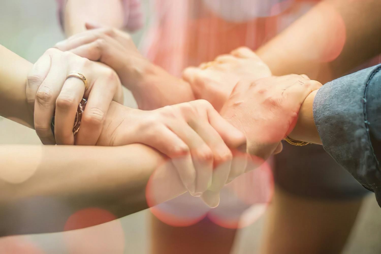 Imagen que muestra manos de tres personas cogiendo el brazo del otro, en forma circular, representando el trabajo en equipo y liderazgo vulnerable.