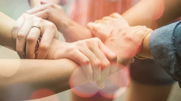 Imagen que muestra manos de tres personas cogiendo el brazo del otro, en forma circular, representando el trabajo en equipo y liderazgo vulnerable.