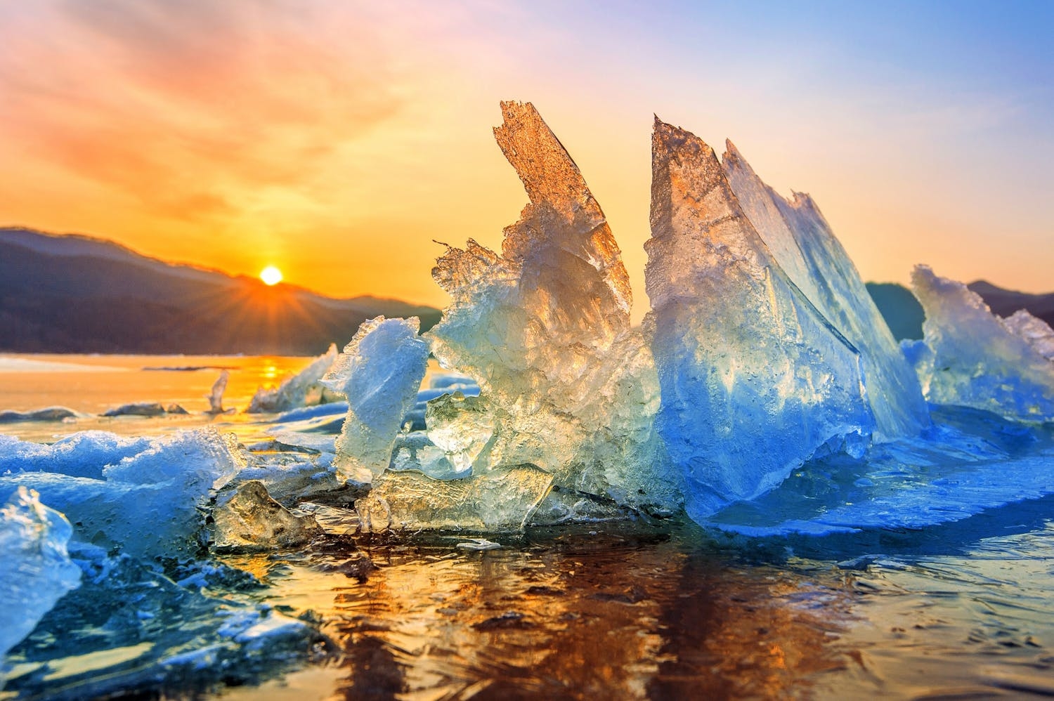 Imagen de un glaciar reditiéndose, con un sol muy brillante encima, representando la nueva era climática: la ebullición global.